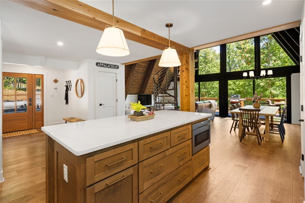 A view of the living area and dining room from the kitchen and the wall of windows overlooking the main deck. 
