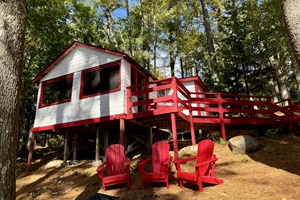 Nestled deep in the woods, this charming white and red cabin offers rustic tranquility with a touch of classic charm
