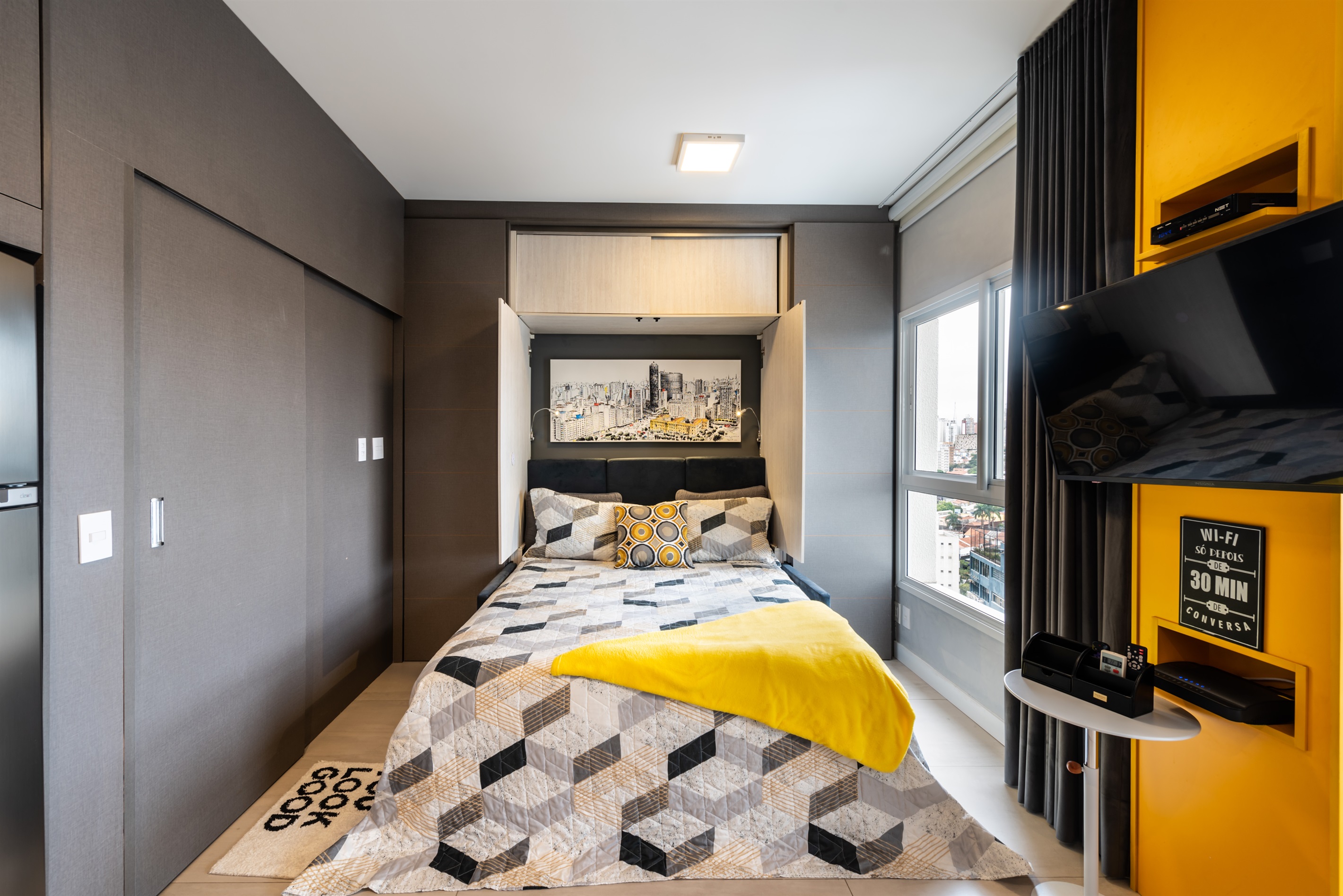 Quarto moderno com cama queen-size, armários planejados e design sofisticado em Pinheiros, perfeito para noites de conforto e praticidade.