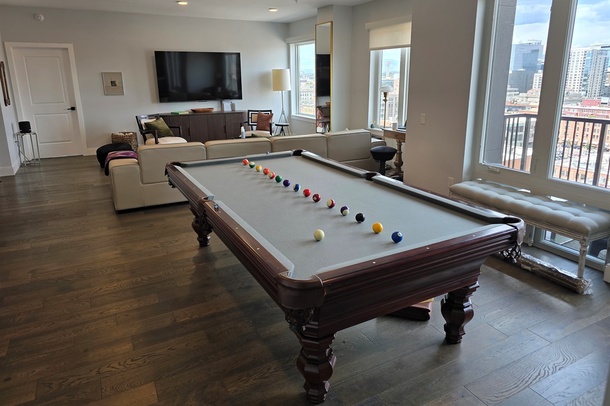 🎱 Living room with custom 9ft pool table, 85" Smart TV, and balcony views.