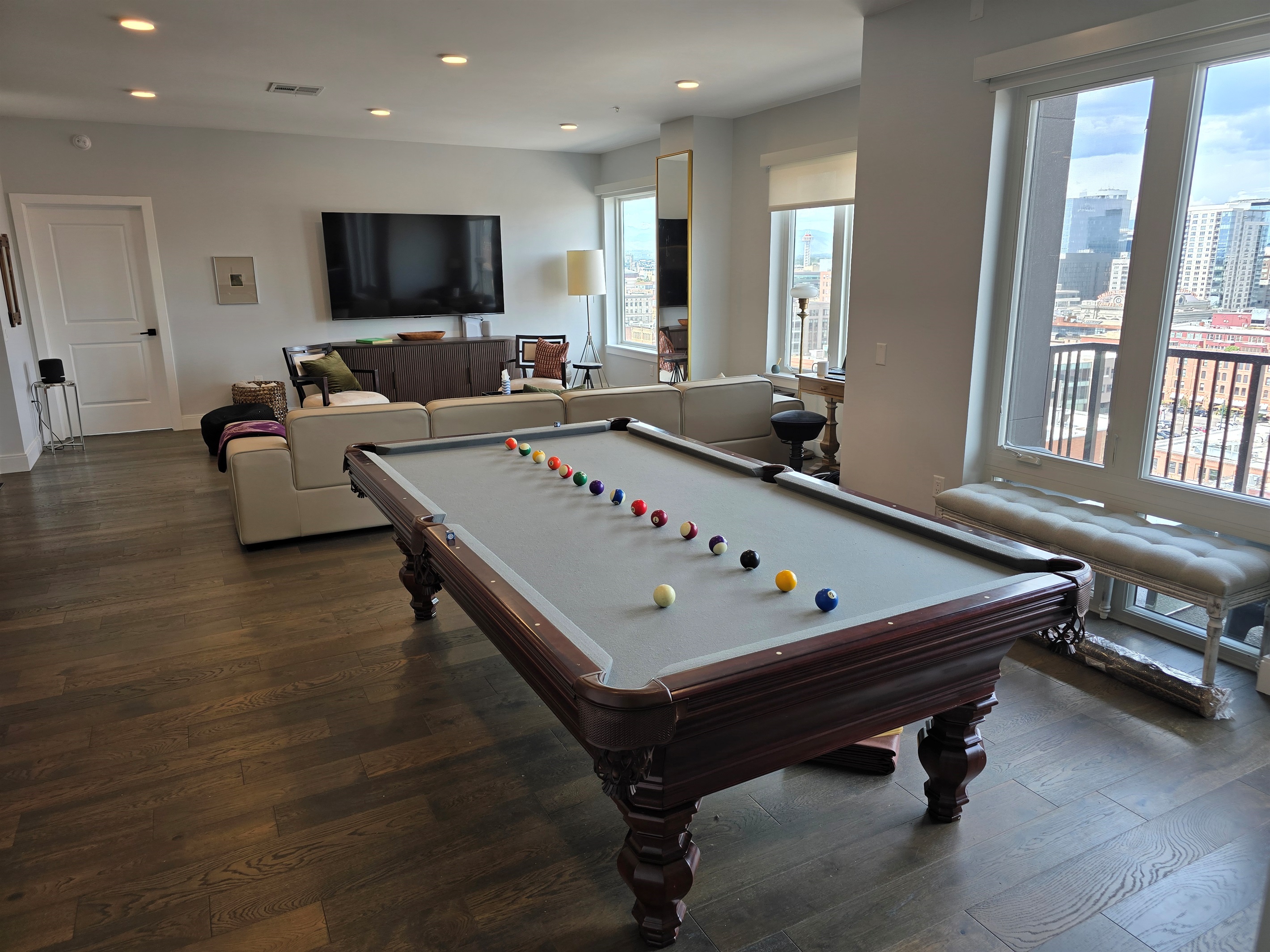 🎱 Living room with custom 9ft pool table, 85" Smart TV, and balcony views.