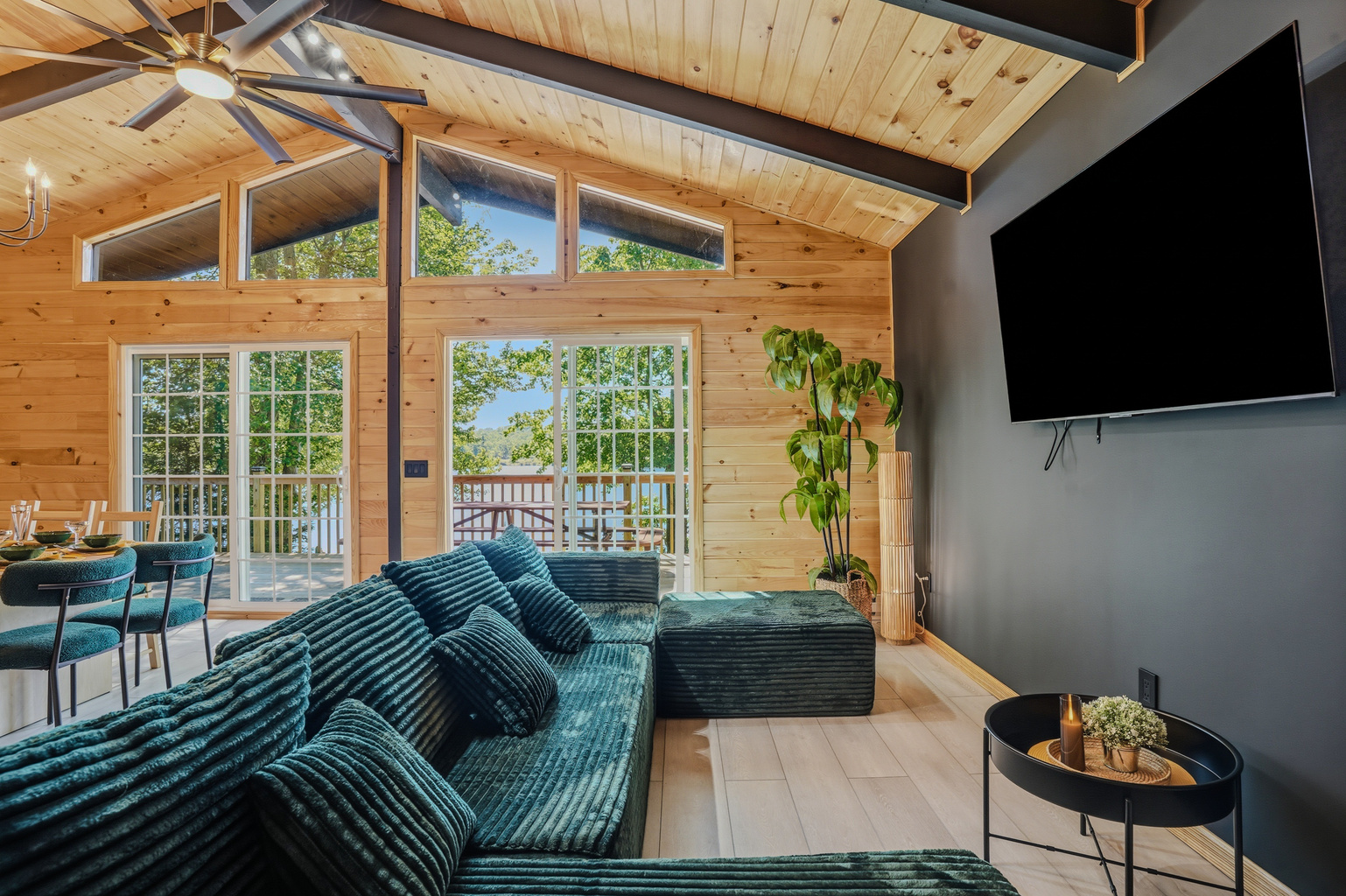  Main living room with teal sectional, vaulted wood ceiling, Smart TV, and lake-view windows