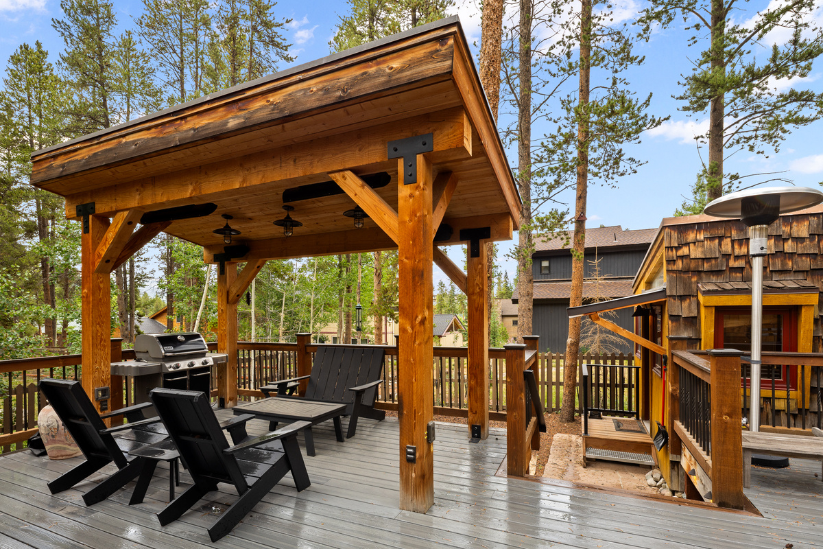 Backyard outdoor living space with covered bar-b-que area and outdoor heaters for cozy apres or after-dinner drinks. 