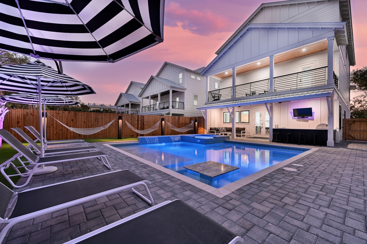 Astroturf yard with Luxury lounges, matching umbrellas, poolside hammocks, putting green, and backyard lighting