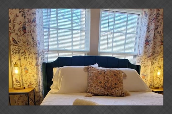 Peaceful bedroom featuring a plush bed with crisp white linens, a velvet headboard, and warm lighting—perfect for a restful night’s sleep.