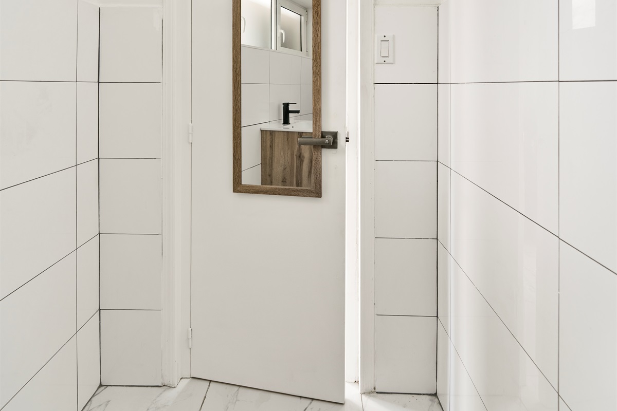 Sleek Half Bath Entrance with Modern Mirror & Neutral Tiles
