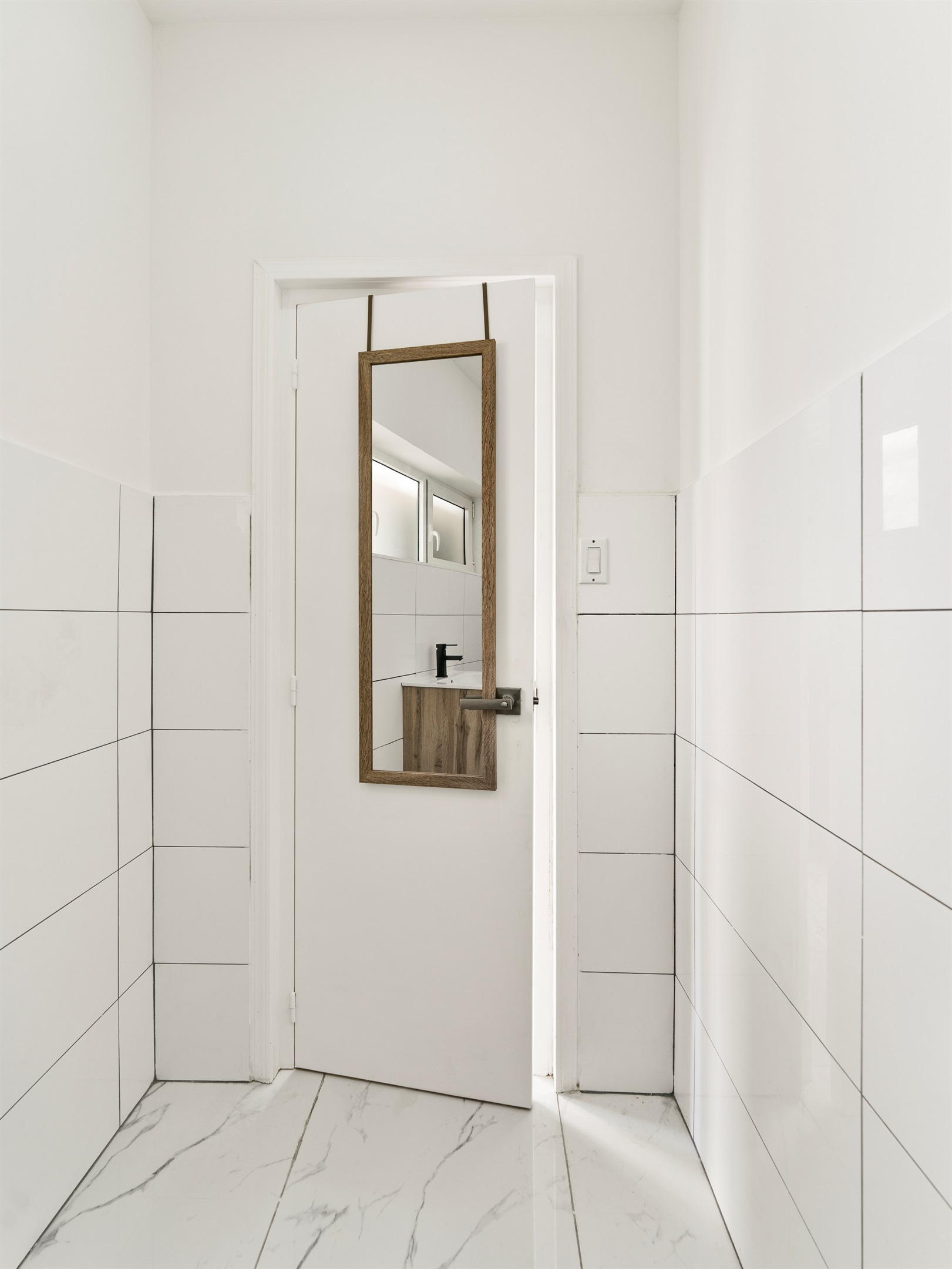 Sleek Half Bath Entrance with Modern Mirror & Neutral Tiles