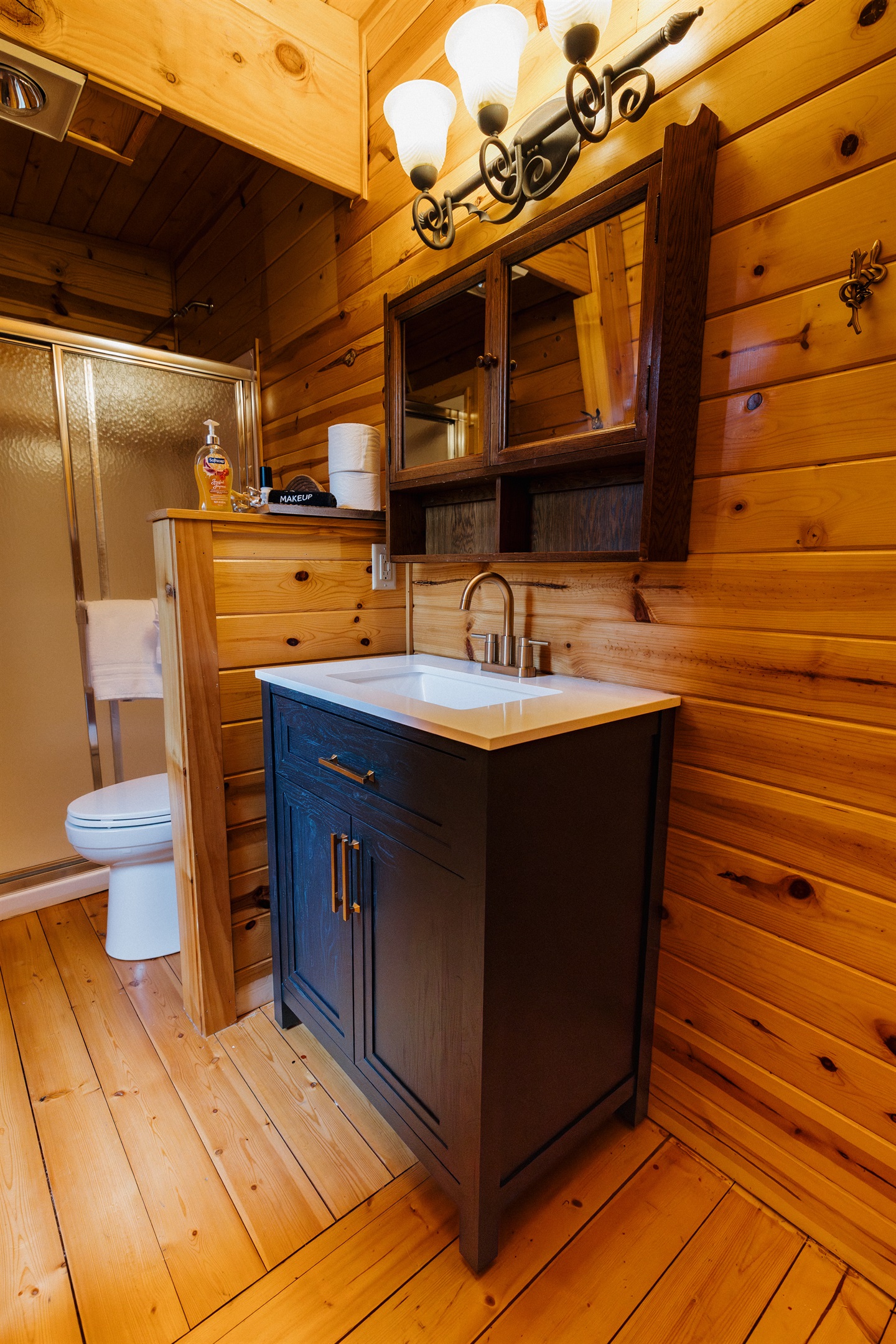 Poppywood Pines’ thoughtfully designed bathroom features generous counter space, ample storage, warm wood finishes, and a modern vanity—offering comfort and convenience for families and groups enjoying a relaxing White Mountains cabin getaway.