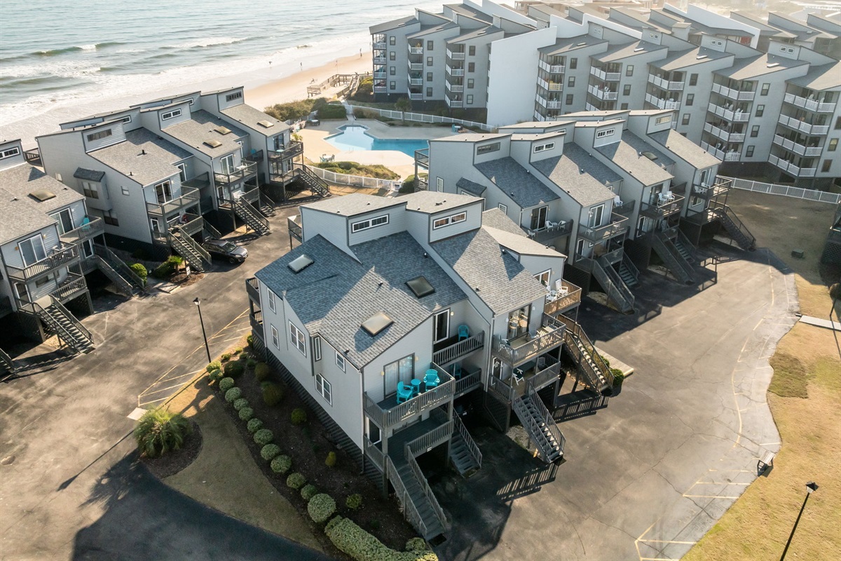 Aerial view showing the oceanfront buildings, community pool, and easy beach access