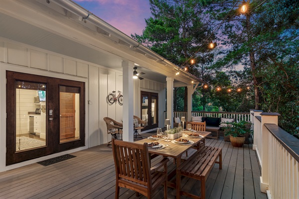 The spacious porch is softly lit by glowing string lights, creating the perfect setting for evening dinner and conversations.