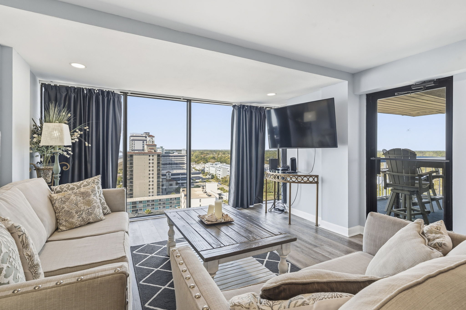 Living room seating with a wall-mounted smart TV and balcony access