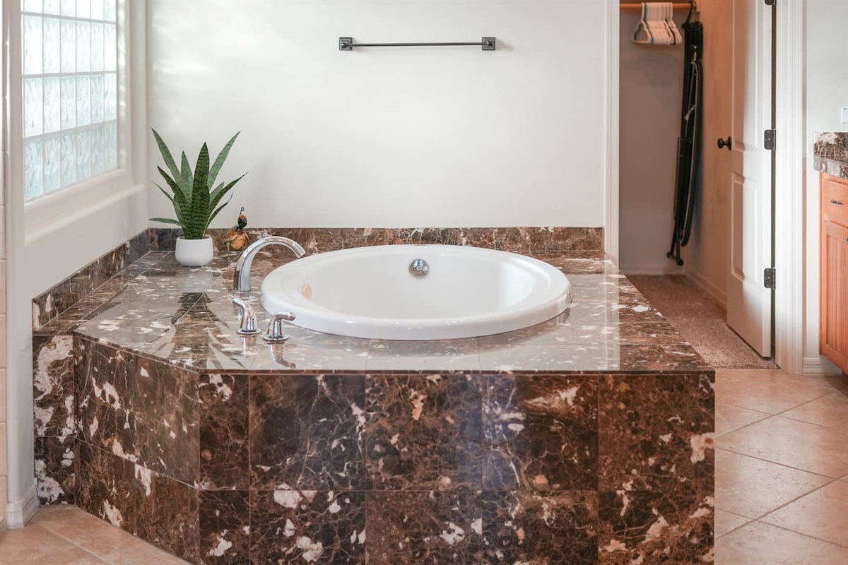 Spa-style soaking tub surrounded by marble-look stone, perfect for unwinding after a day out.