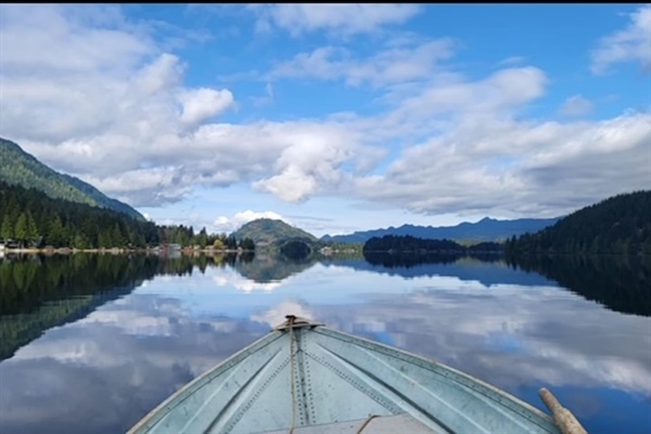 View from a small fishing boat with the lake and sky reflected in the water.