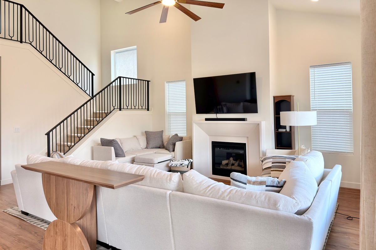 Stylish open-concept living room with elegant staircase, cozy seating, and abundant natural light.