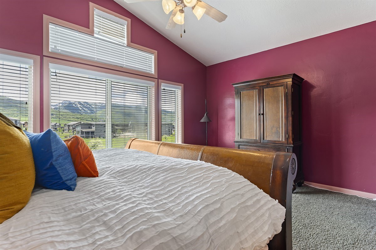 Wake up to natural light and serene vistas in this beautifully appointed primary bedroom, where bold accents meet tranquil comfort.
