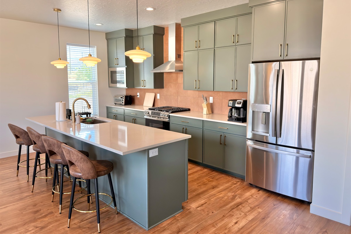 Chef’s dream kitchen with forest-green cabinetry, quartz counters, and a large island with seating.
