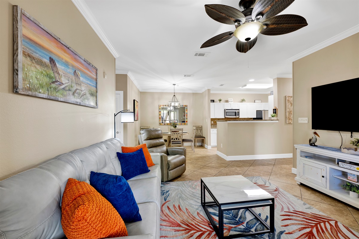 Living room with leather sleeper sofa, recliner, arm chair, ceiling fan and wall mounted smart TV 