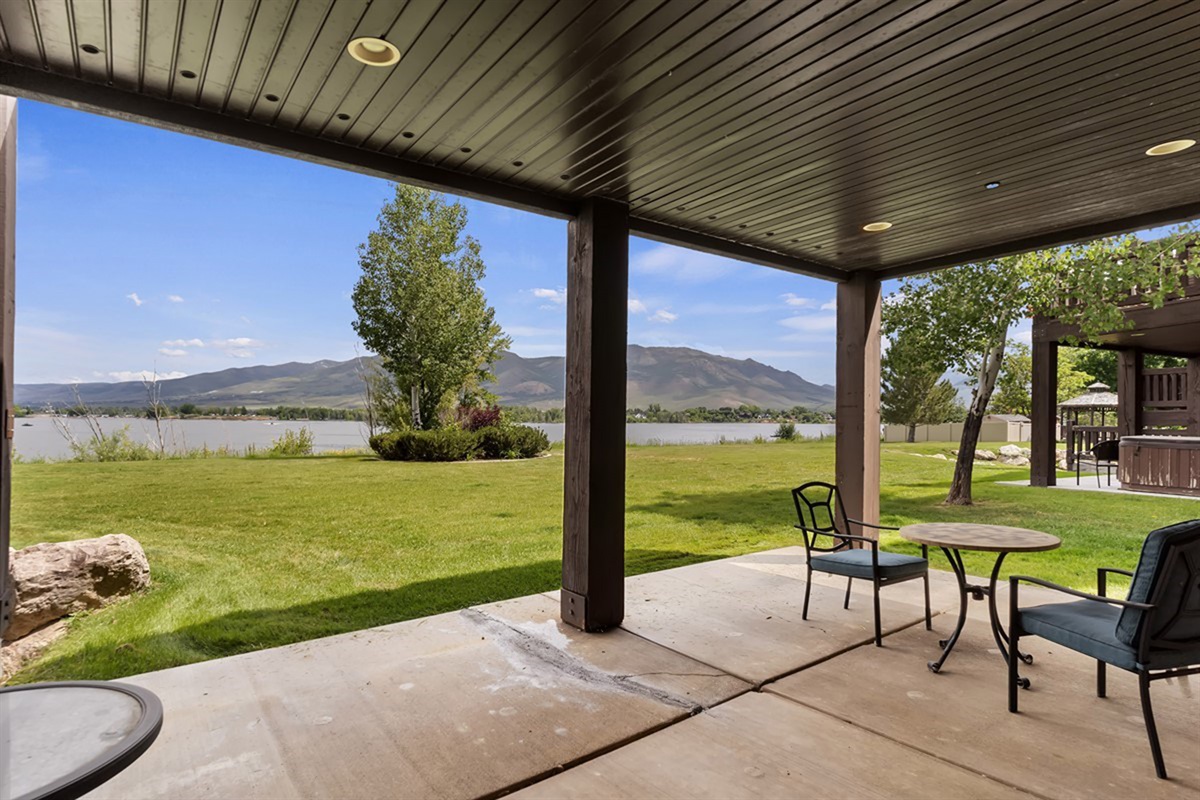 Spacious covered outdoor lounge overlooking lush green space and water—perfect for peaceful mornings or evening gatherings.