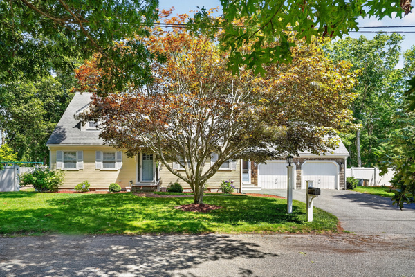 Charming front exterior with mature landscaping and generous parking.