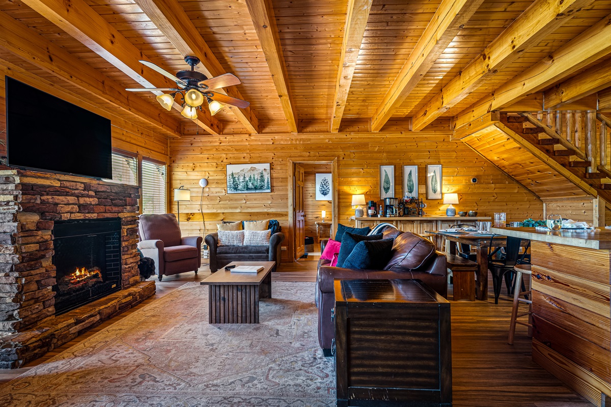 Spacious open-concept living area with fireplace, comfortable seating, and seamless flow into the kitchen and dining space—perfect for large groups and gathering