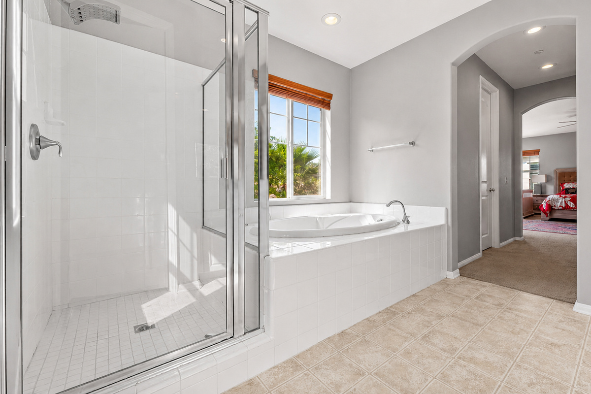 Bathroom with a glass shower, soaking tub, and easy access from the nearby bedroom.