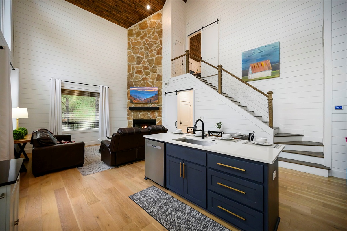 Open-concept living with soaring ceilings and a dramatic stone fireplace.
