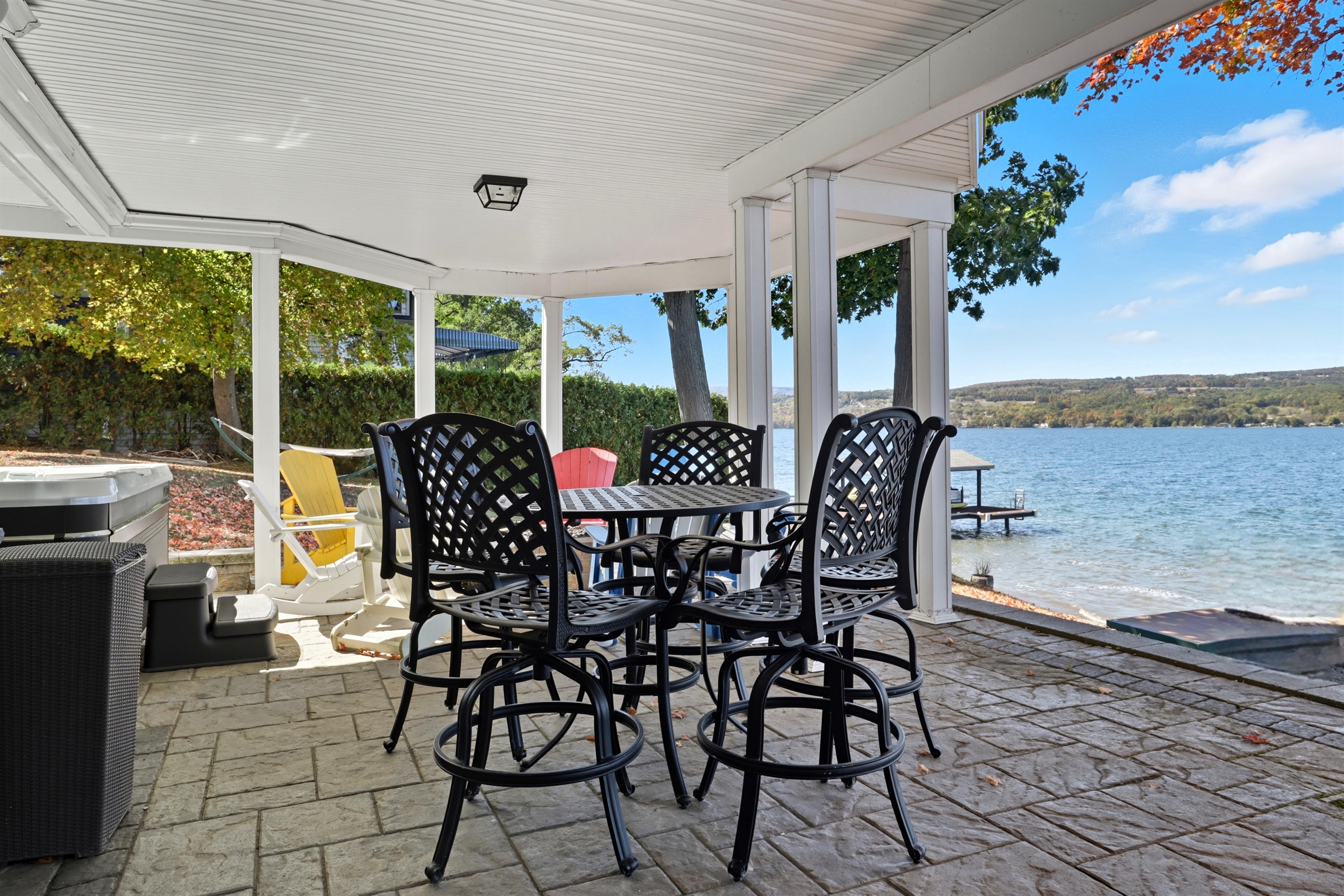 Covered ground level patio with dining area, fire pit, Hot tub and outdoor shower overlooking the lake.