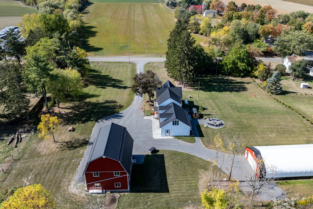 Bird’s-eye view of the peaceful property with farmhouse, barn, and open green pastures