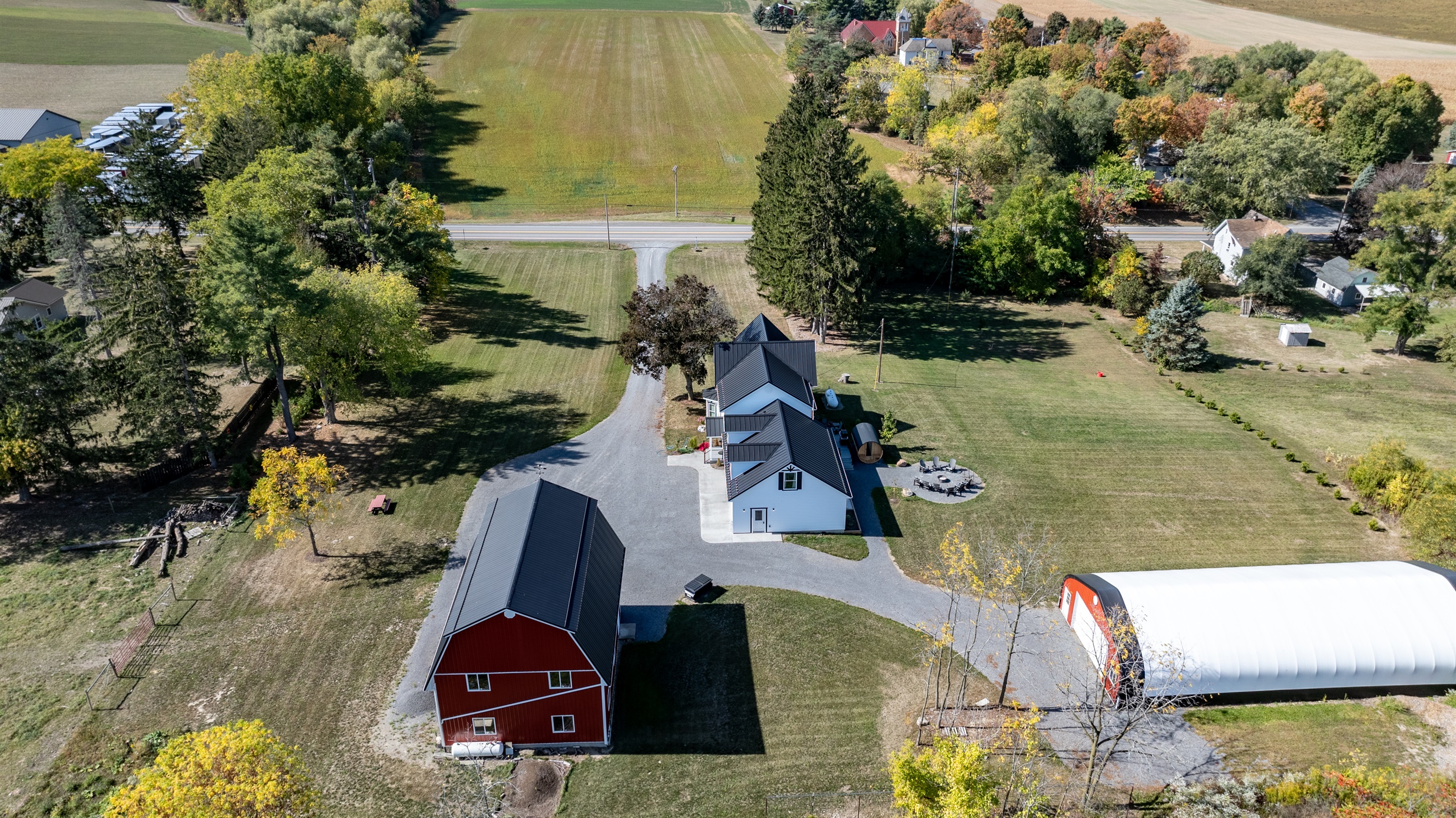 Bird’s-eye view of the peaceful property with farmhouse, barn, and open green pastures