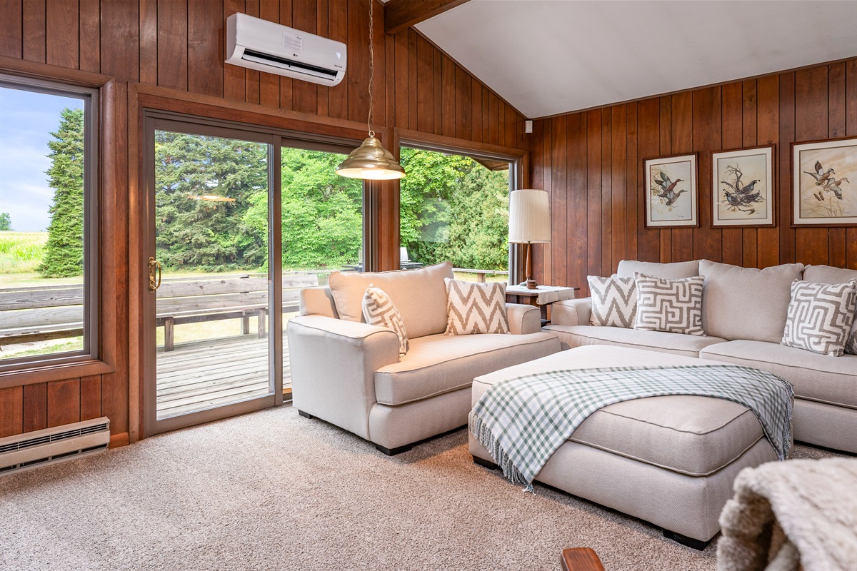 Relax in the bright, airy living room featuring plush seating, sliding doors to the deck, and scenic views of the surrounding greenery.