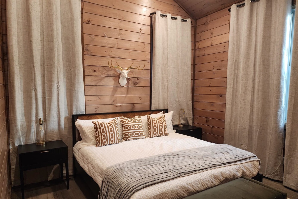 Queen bedroom with accent wall, reading lamps, and ensuite access.