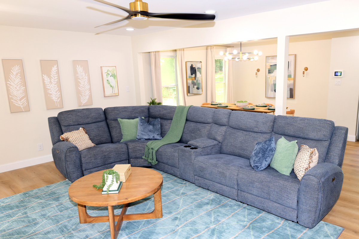 Comfortable main living room with large sectional, TV, and open access to the dining area