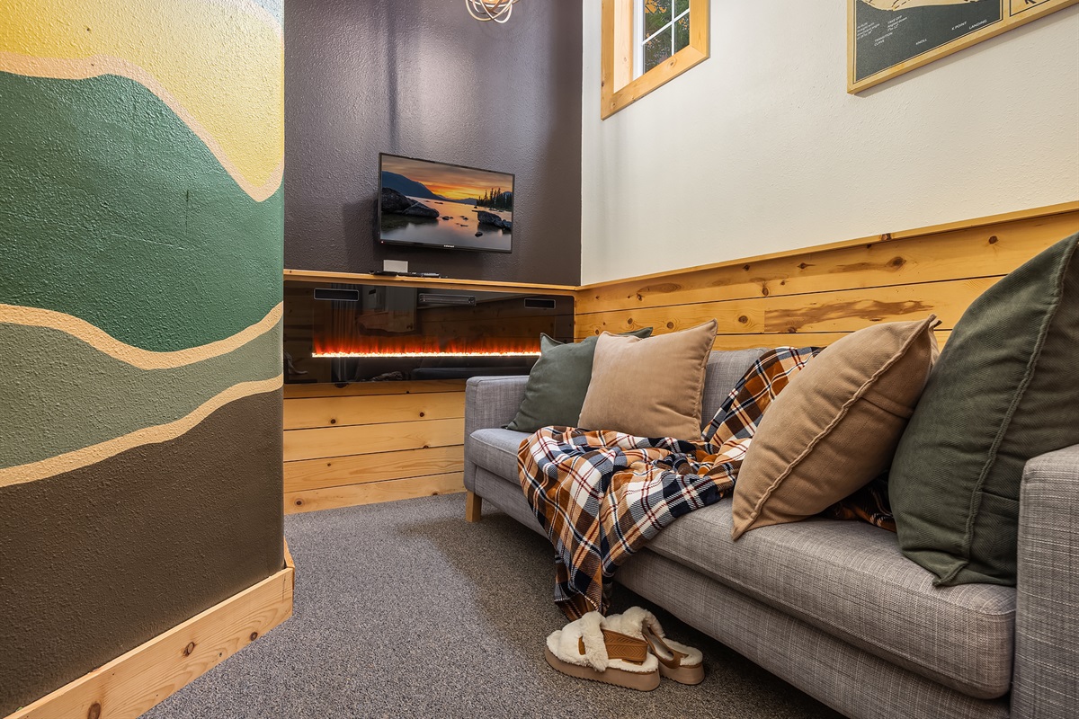 Downstairs sitting area with arcade game, electric fireplace and TV