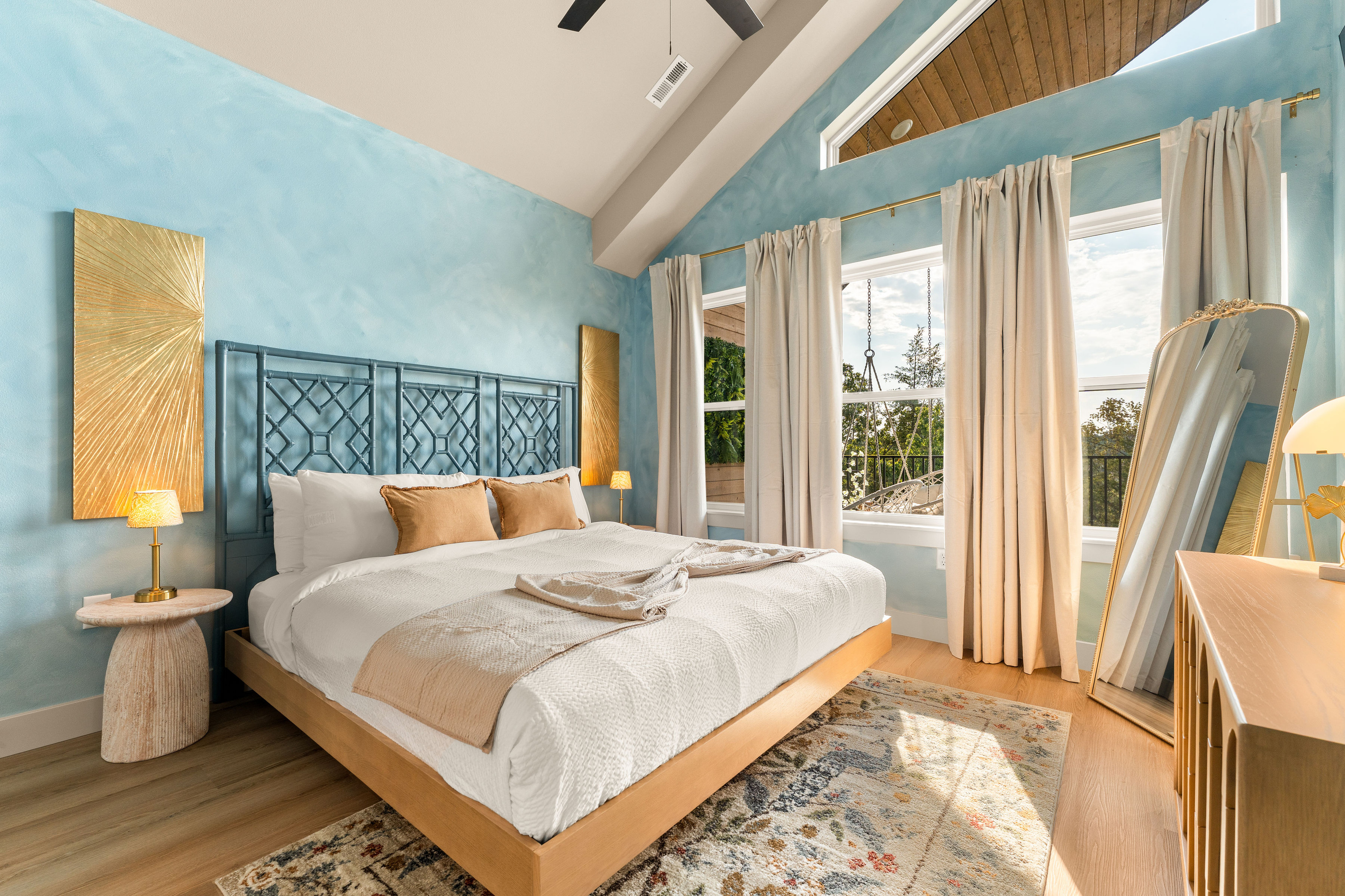 Soaring ceilings, dreamy blue walls, oversized windows, and a striking statement headboard make this light-filled king suite feel like a retreat of its own.