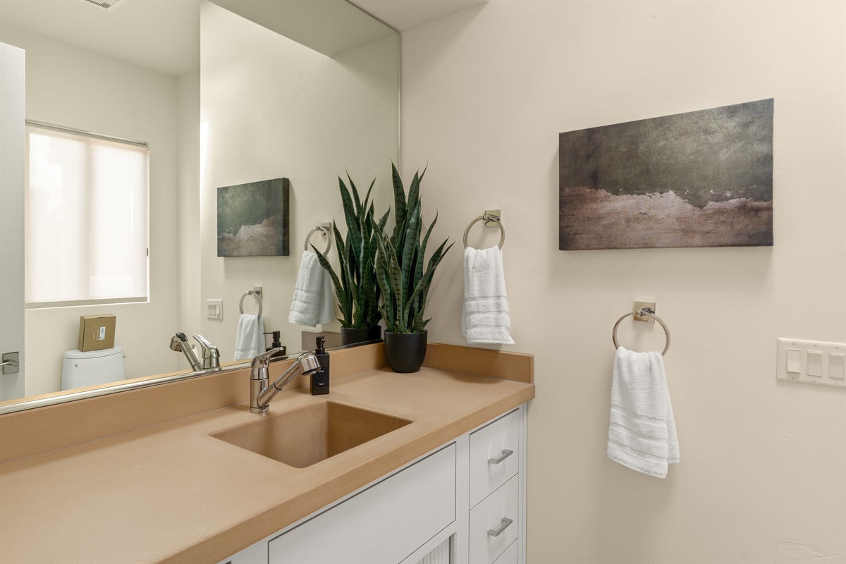 Earthy elegance. This well-appointed guest bath with a corner cozy shower features warm, sand-toned countertops, desert greenery, and a bright, clean design to make your morning routine a breeze