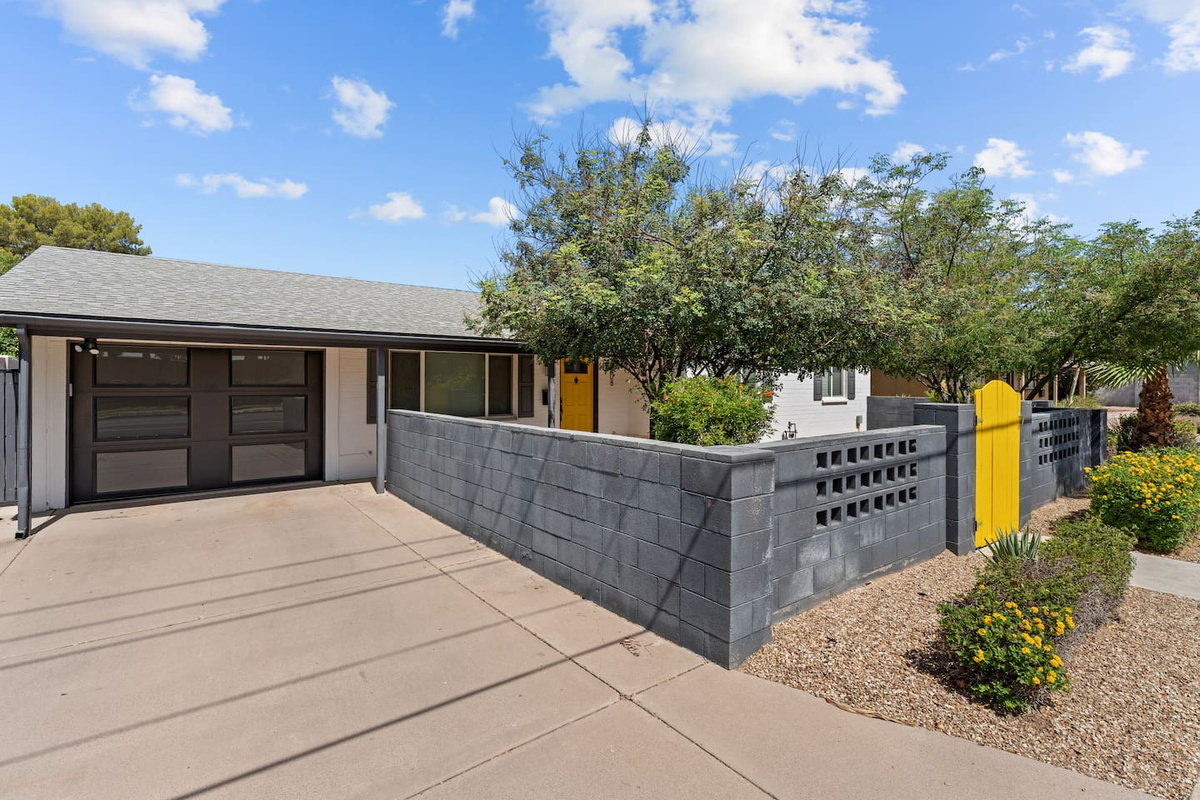 Front exterior with driveway, garage, and yellow gate entry.