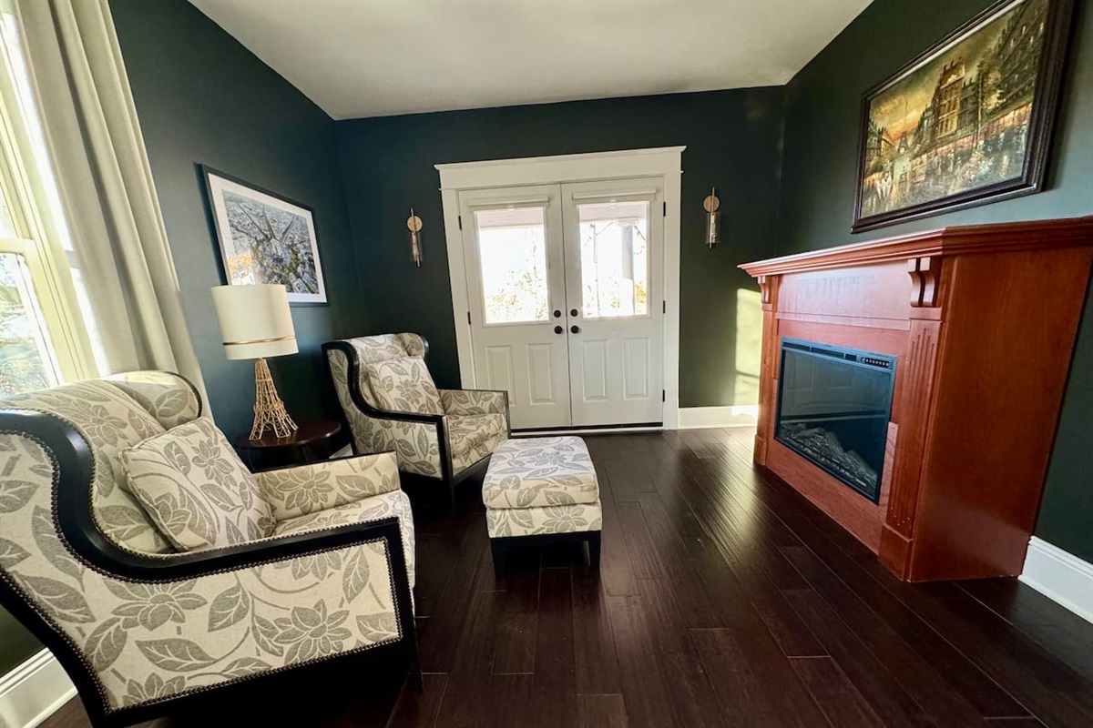 Electric fireplace, sitting room and access to covered balcony in the Paris Suite.