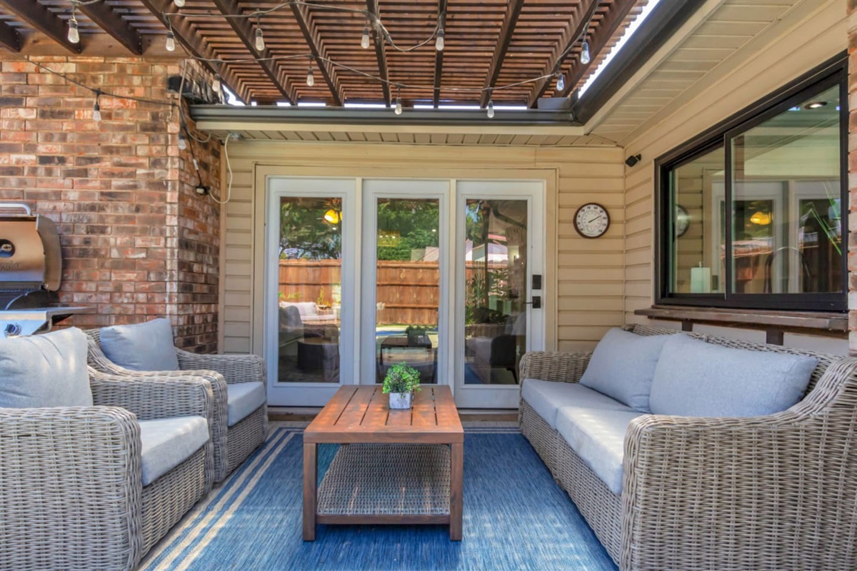 Zoomed in view of the covered patio's sitting area, coffee table, and poolside vibes. 