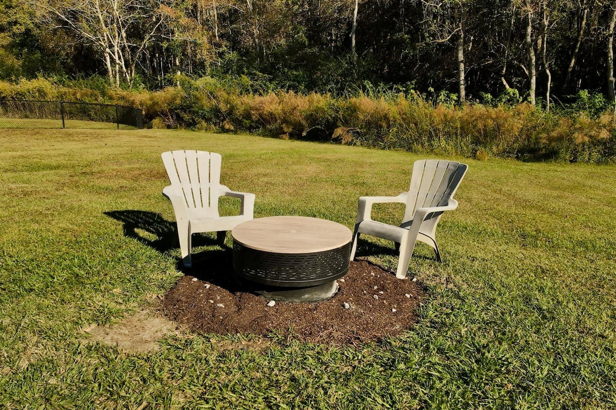 Two Adirondack-style chairs surround a circular fire pit, creating the perfect spot for evening relaxation.