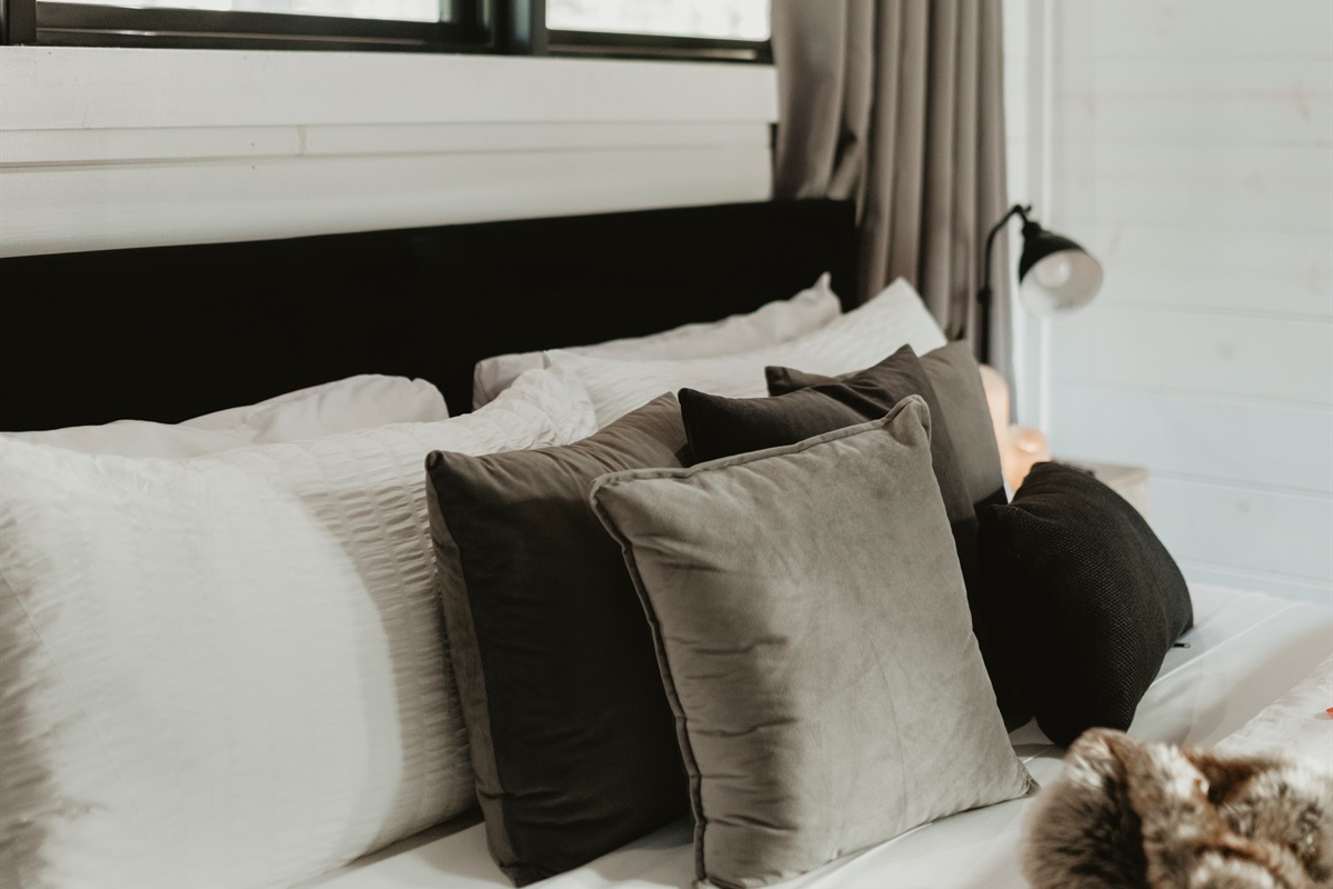 Soft textures and layered pillows create a cozy, inviting bedroom retreat. Perfect for sinking in after a day of adventure and waking up refreshed for peaceful mornings in the pines.