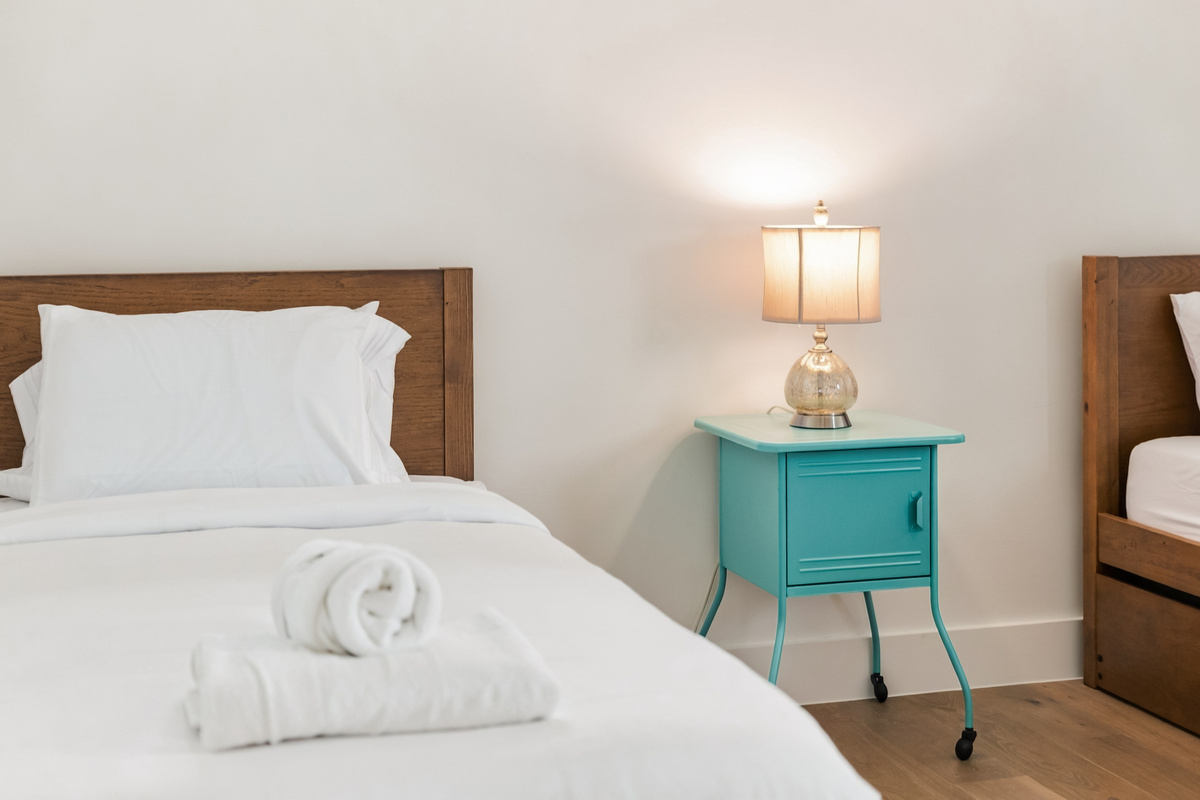 Crisp linens and a teal nightstand bring a playful touch to this twin bed.