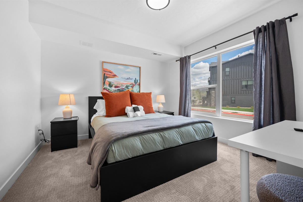 Light-filled bedroom with large windows and comfortable bedding.