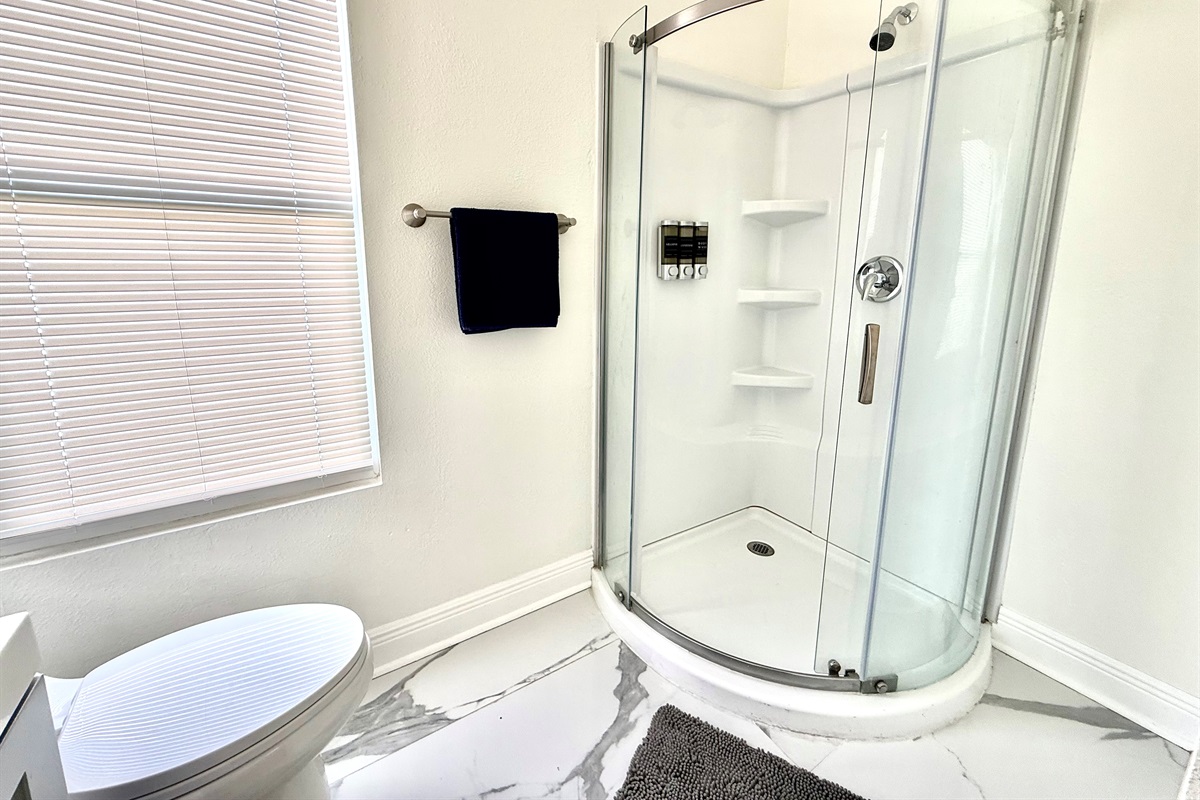 Bright and thoughtfully designed, this full bathroom offers a space-saving walk-in shower with smooth sliding doors and built-in shelving for a clutter-free stay.