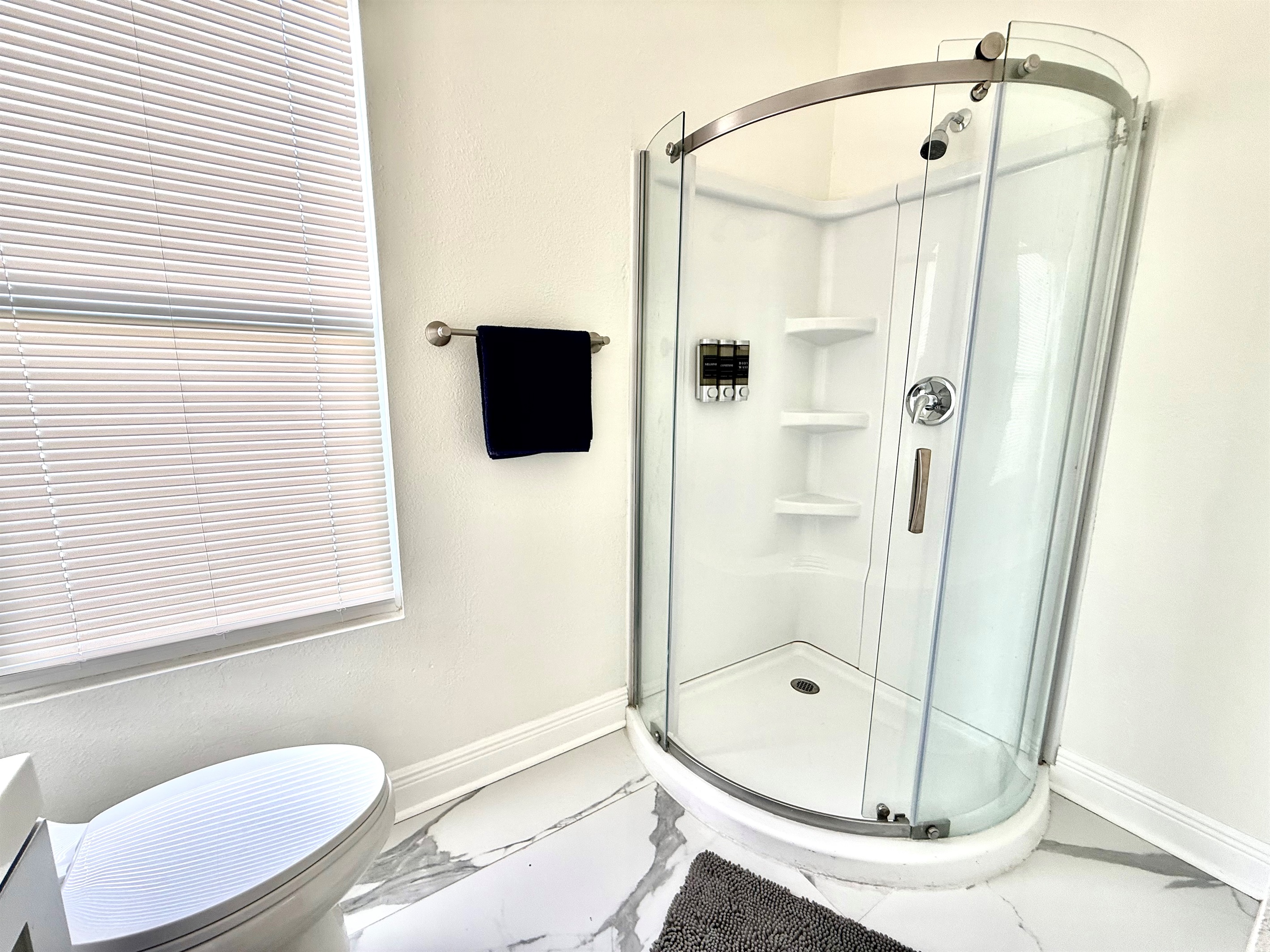 Bright and thoughtfully designed, this full bathroom offers a space-saving walk-in shower with smooth sliding doors and built-in shelving for a clutter-free stay.