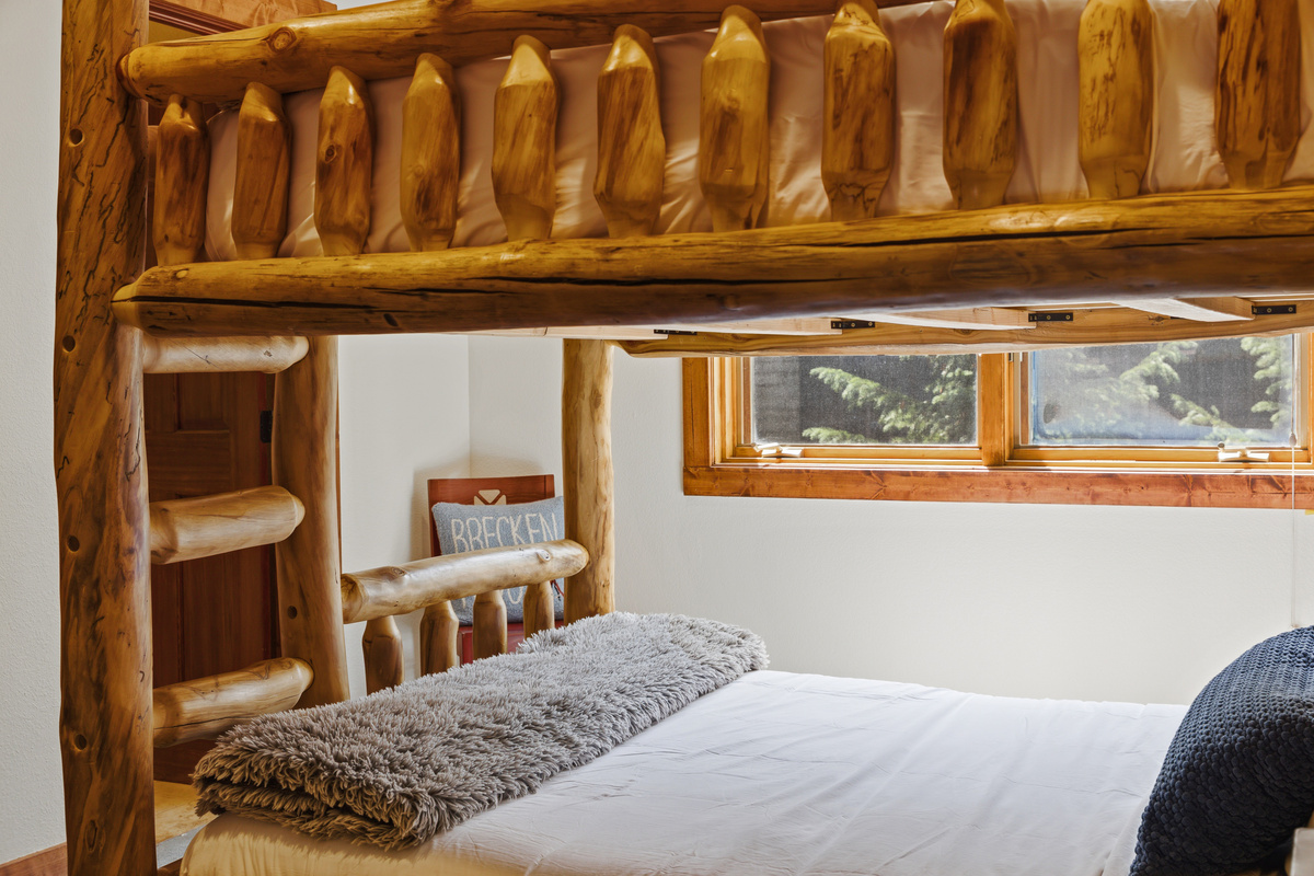 Upper level guest room with Queen-over-Queen bunk, tv, large window, and attached bathroom with shower. 