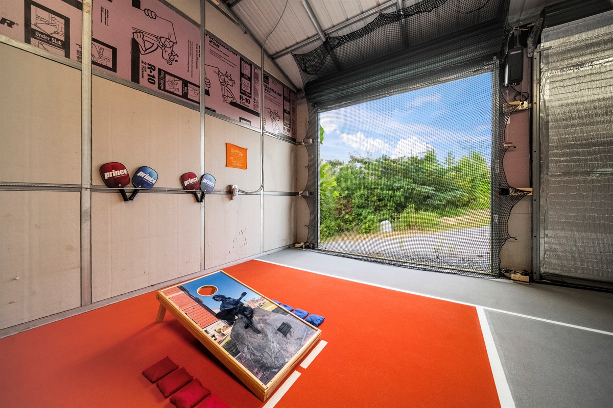 Play corn hole with Dolly. The white lines on the pickle ball court are where to set the bases for adult play. Children should play at a closer distance.