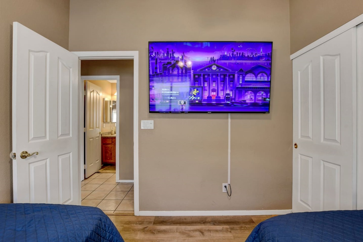 Twin room with smart TV, closet storage, and easy bath access