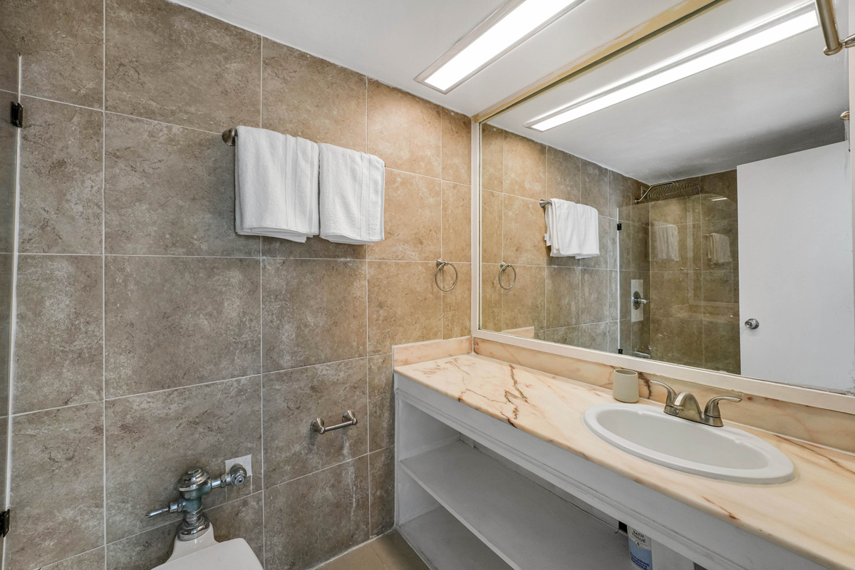 The bathroom vanity offers a single sink, large mirror and fresh towels, with a hairdryer provided.