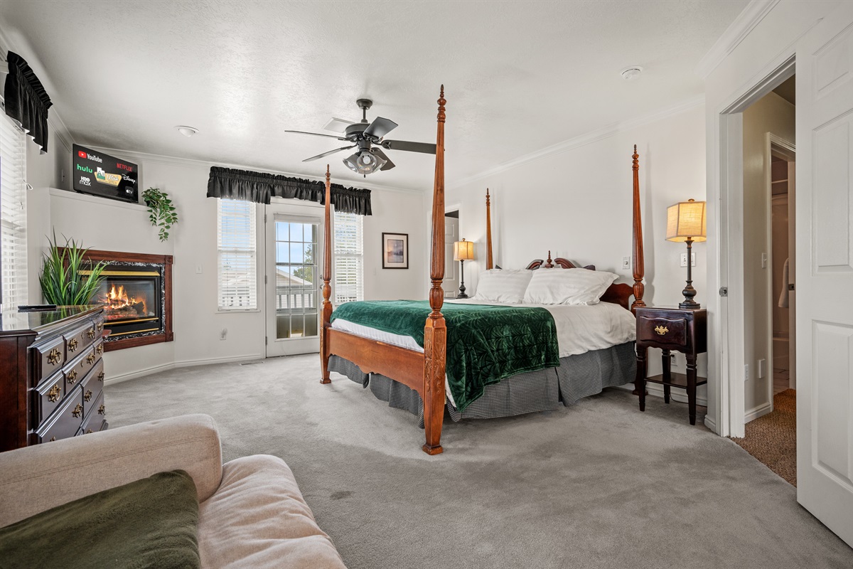 Spacious primary bedroom featuring a luxurious king bed, cozy seating area, and fireplace.