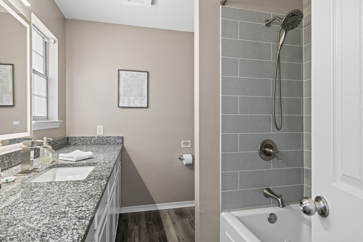 Sleek, updated finishes throughout — tiled shower surround, quartz countertops, and plenty of natural light